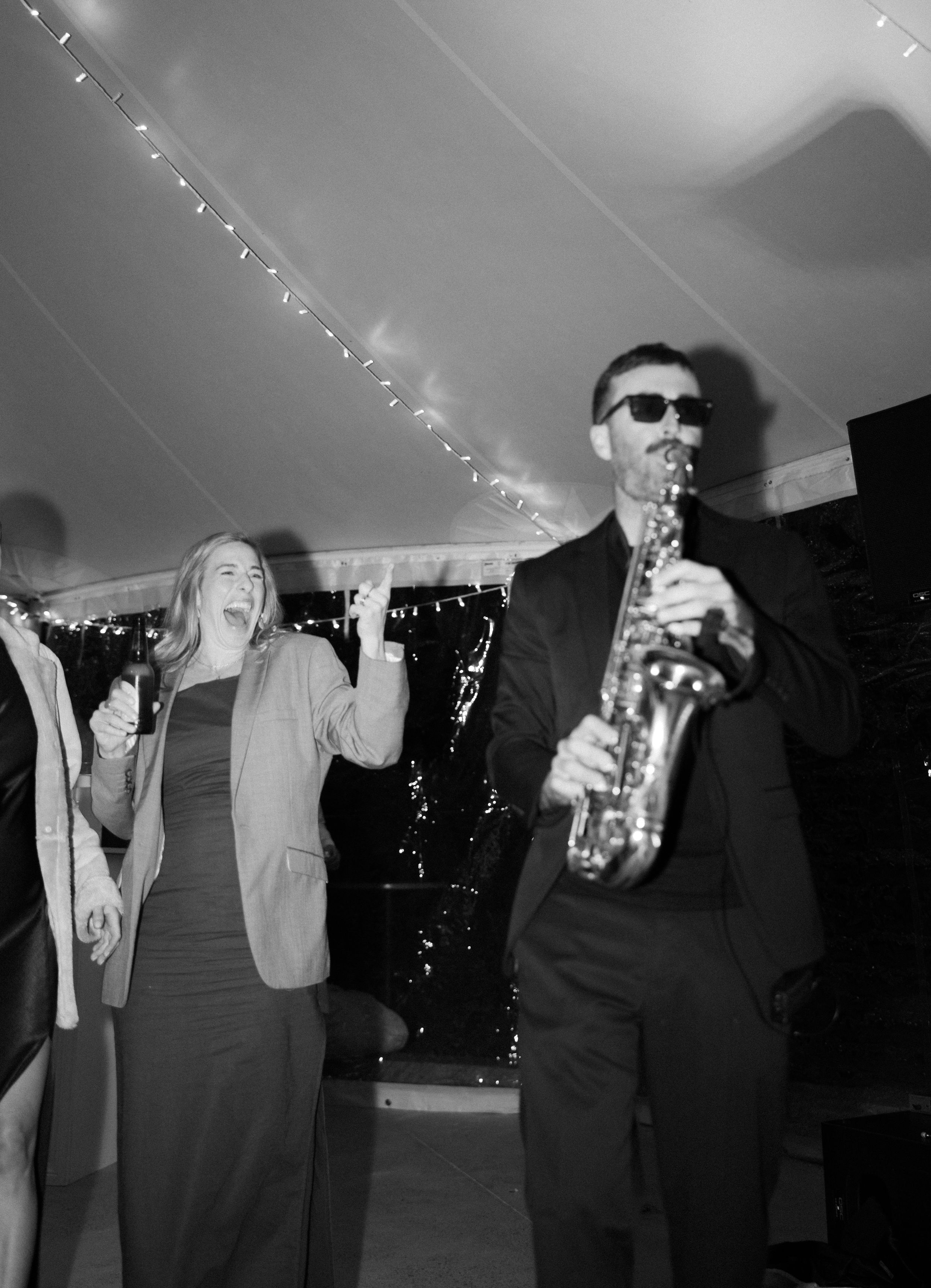 Wedding party members raising champagne glasses in a celebratory toast under twinkling lights.