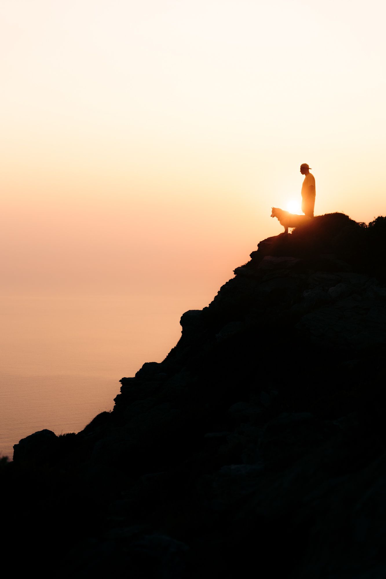 coucher de soleil au moulin mattei, un homme et son chien sont en haut de la falaise qui domine le cap corse