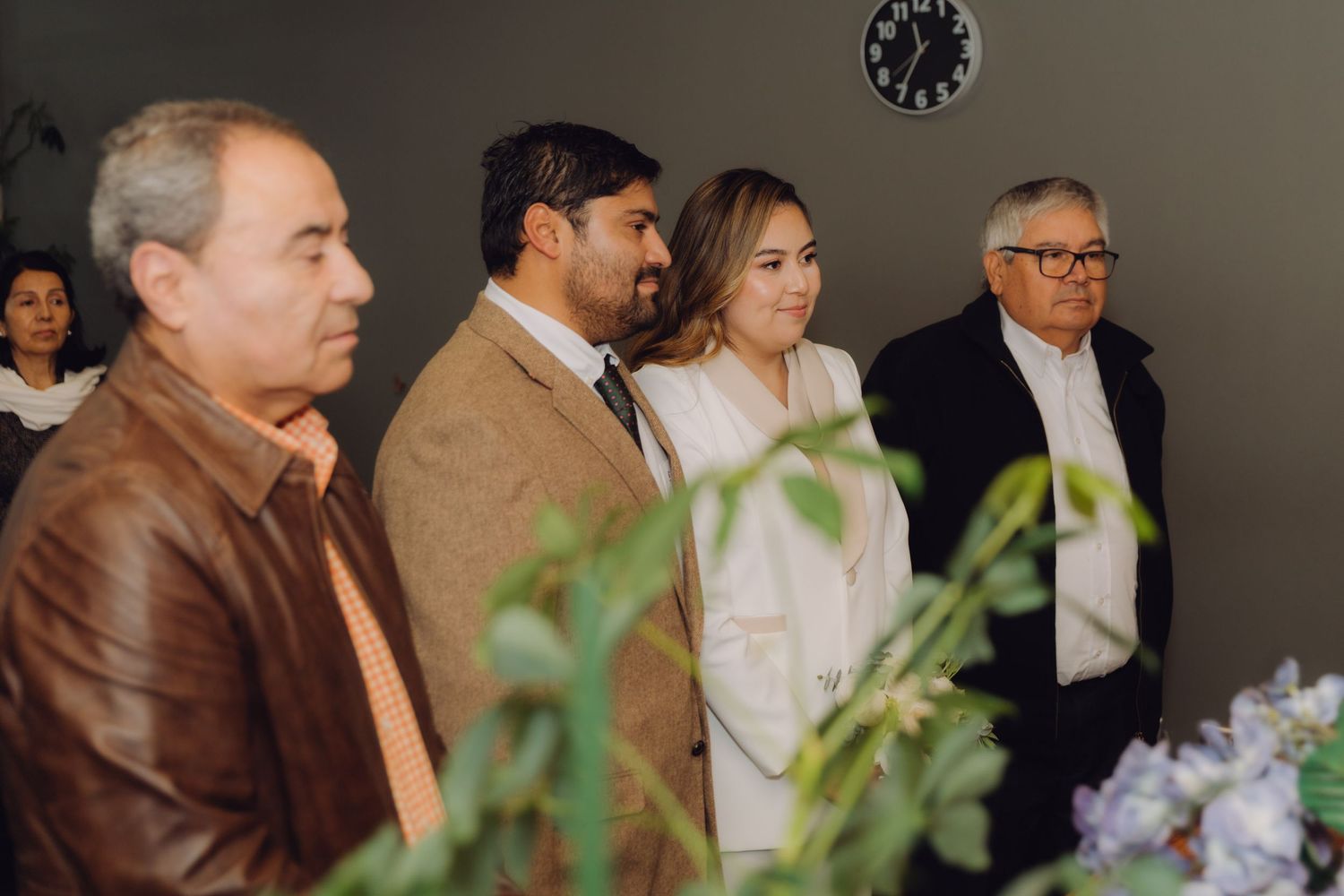 Wedding party standing in row during intimate civil ceremony with floral decorations.