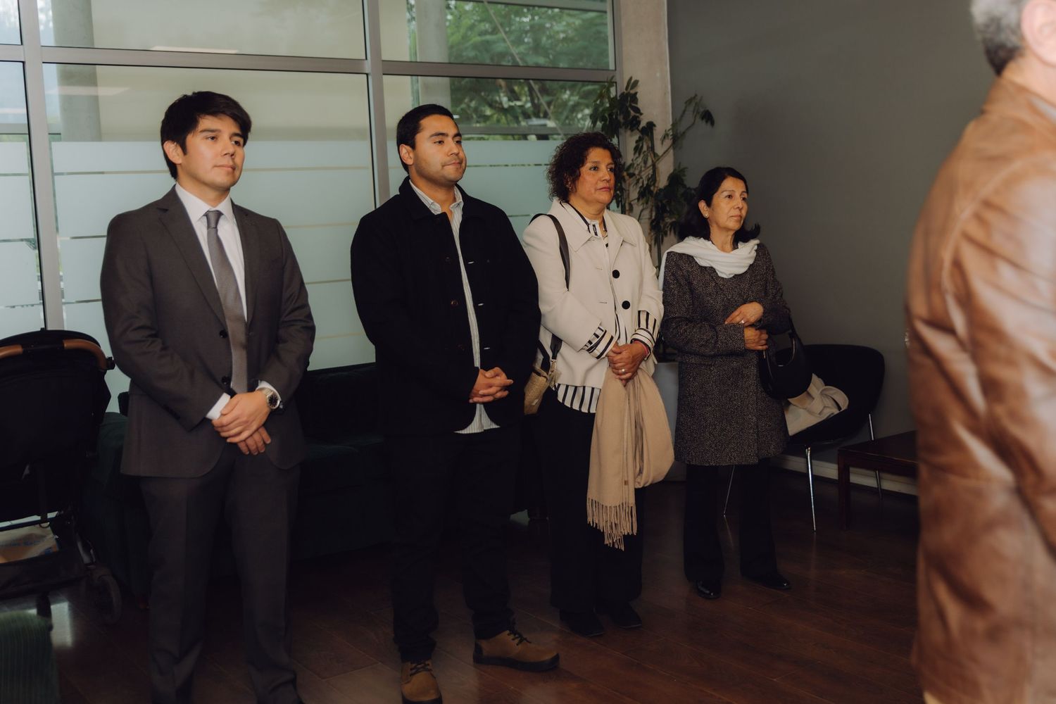 Four formally dressed guests standing attentively during indoor civil wedding ceremony.