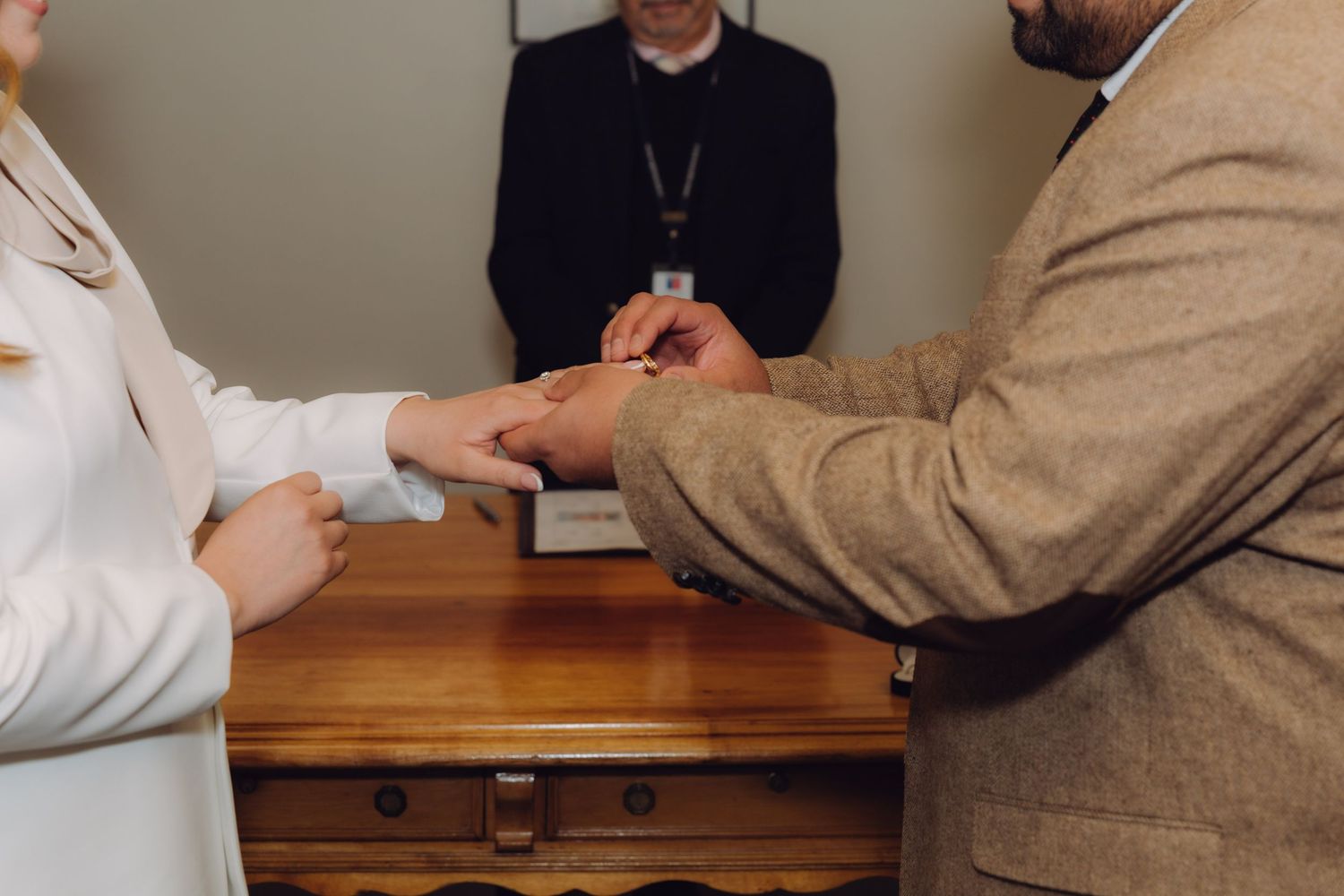 Close-up of couple exchanging wedding rings before officiant at civil marriage ceremony.
