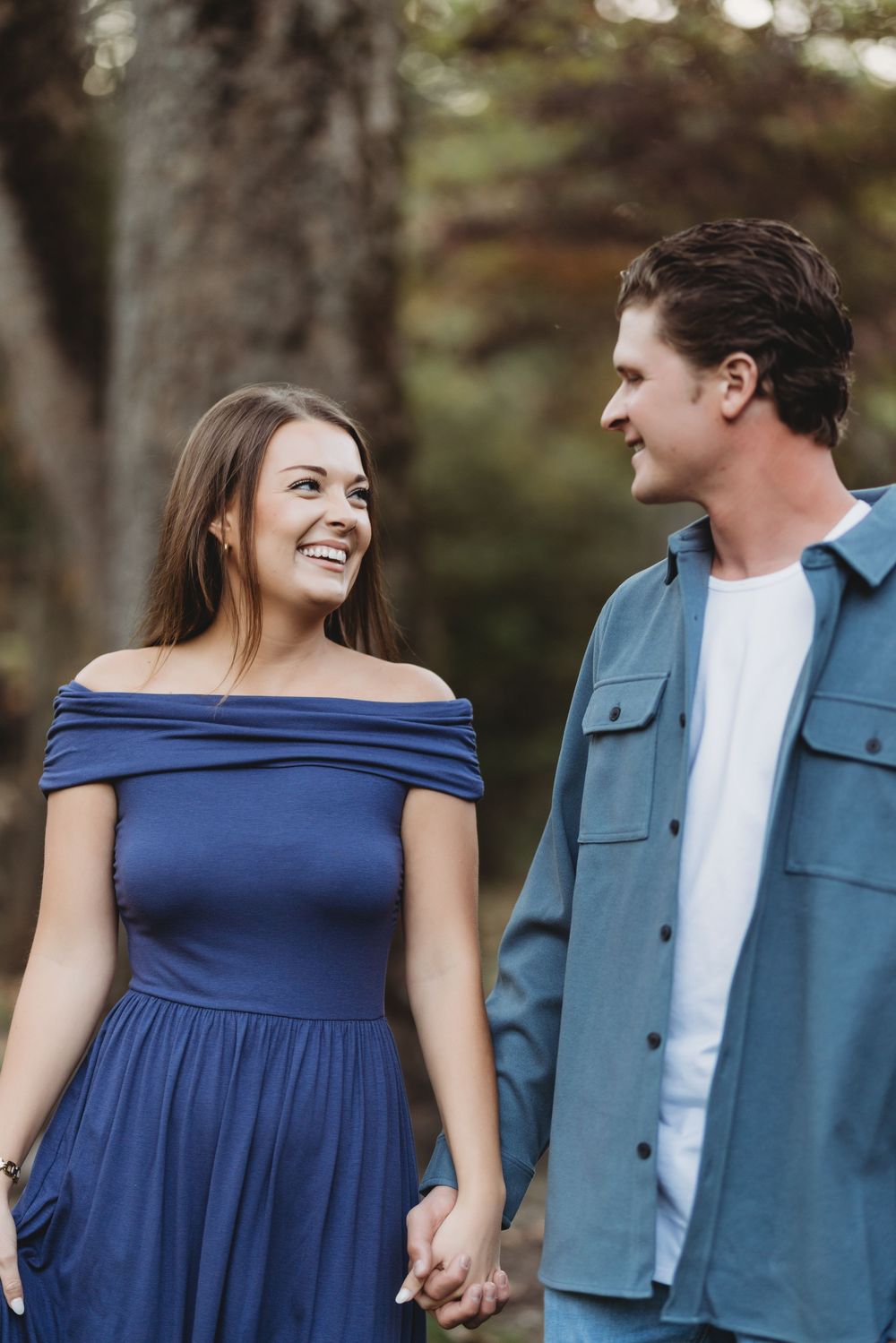 A couple in casual attire shares tender moments against a natural outdoor backdrop.