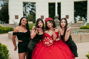 A celebration party posed for photos in front of a classic white building exterior.