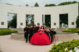 A red formal dress contrasts against white architectural walls in an elegant outdoor setting.