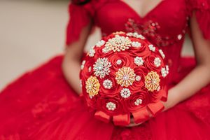 Close-up details of red and gold bouquet with crystal embellishments and ornate decorative elements.