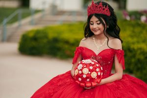 A glamorous red ball gown with gold embellishments captured in an outdoor setting.