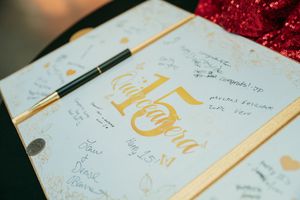 A collection of handwritten cards with gold calligraphy and text details spread out on a red glittery surface.