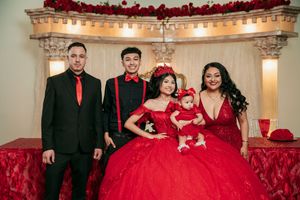 A formal event venue decorated in red and white with elegant floral arrangements and lighting.