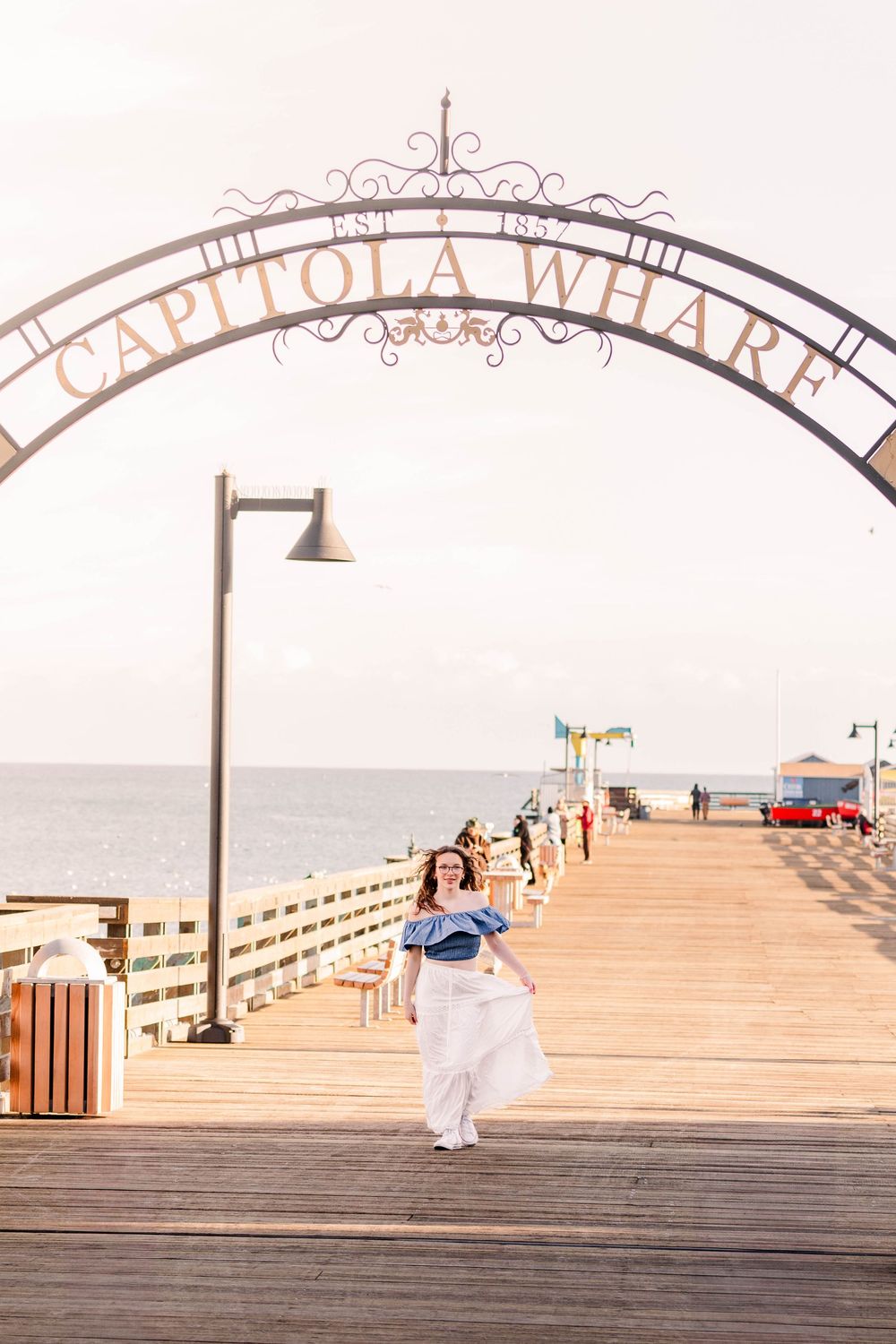 A sequence of photos showing a person in a white dress walking down wooden boardwalk steps at a beach.