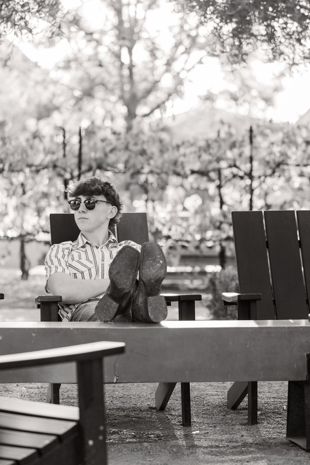 A romantic couple sits together on park benches at different angles in a black and white photo series.