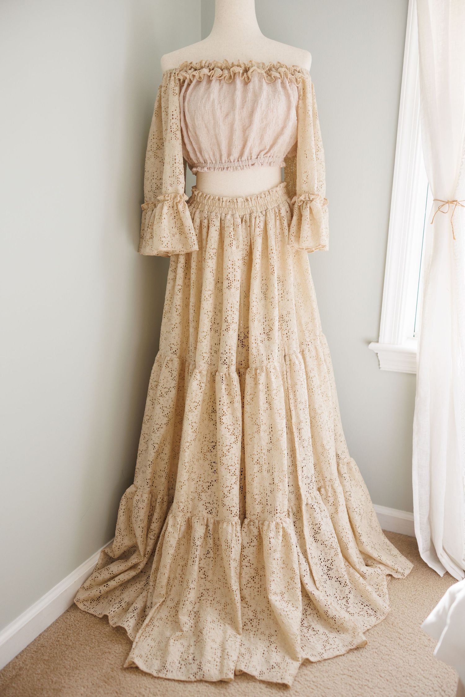 Vintage cream-colored maxi dress with puff sleeves and gathered neckline displayed on white mannequin against pale wall.
