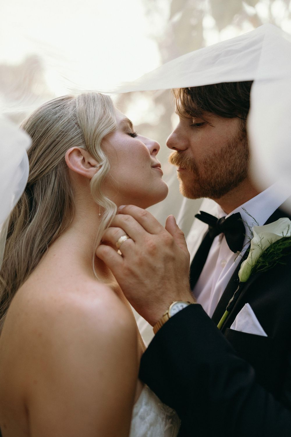 Romantic wedding couple sharing an intimate moment under a veil during their ceremony at The Elms of Coosada in Coosada, Alabama