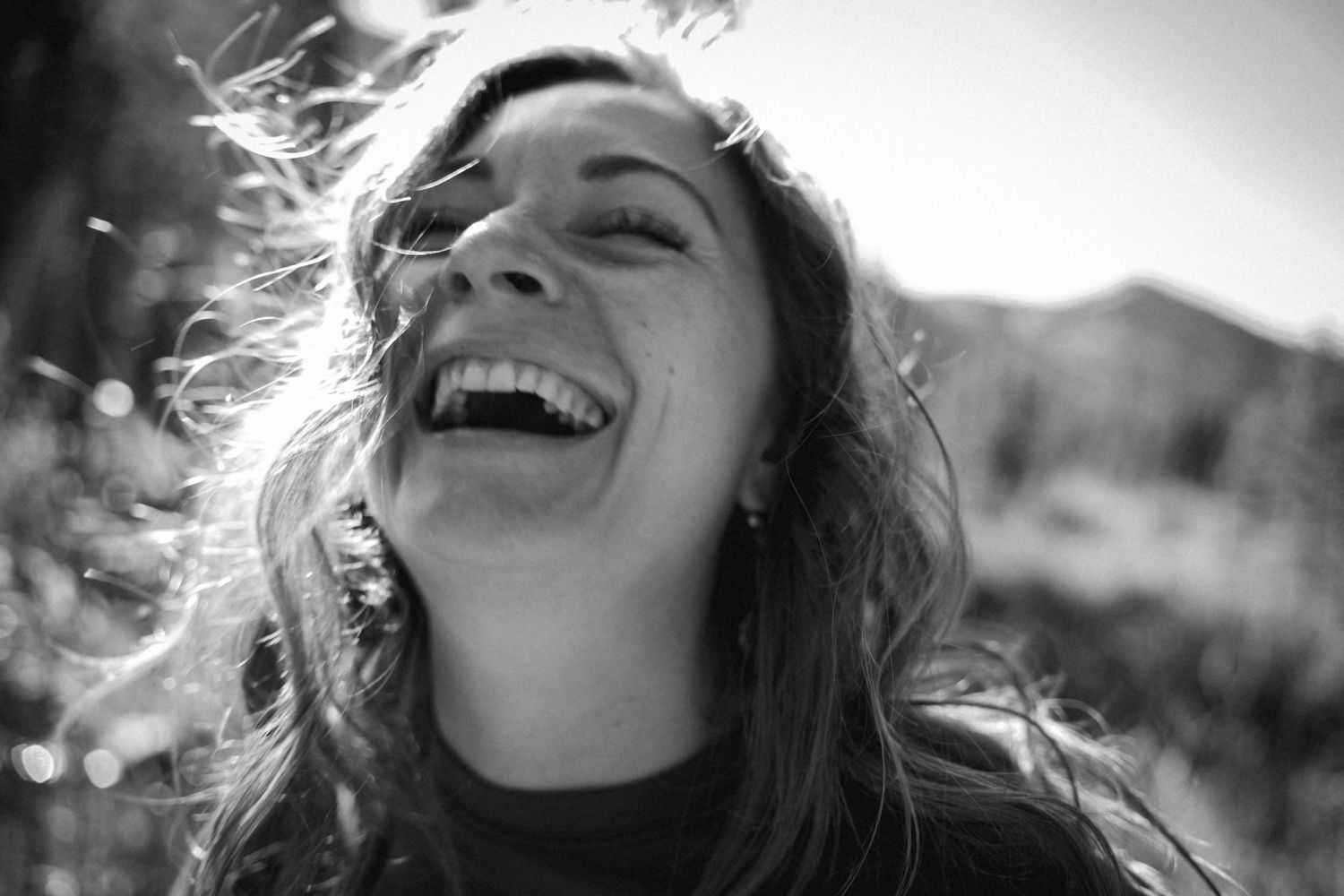 Black and white candid shot capturing joyful laughter outdoors.