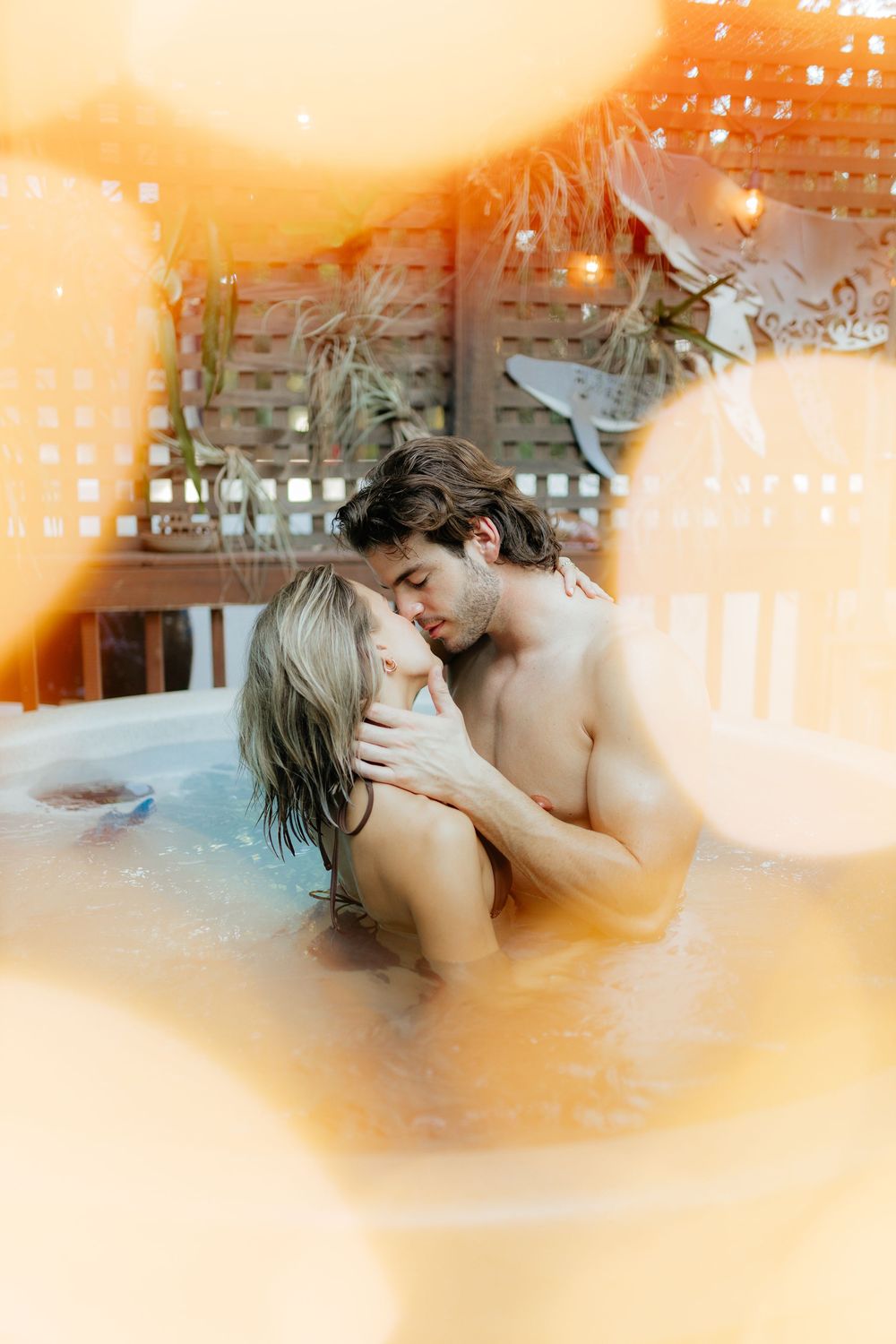 Couple sharing an intimate moment in a private hot tub during a lifestyle couples session, photographed in warm natural light.