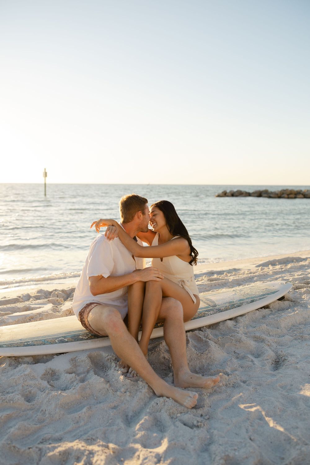 Couple sitting close together on the beach during a lifestyle couples photography session.
