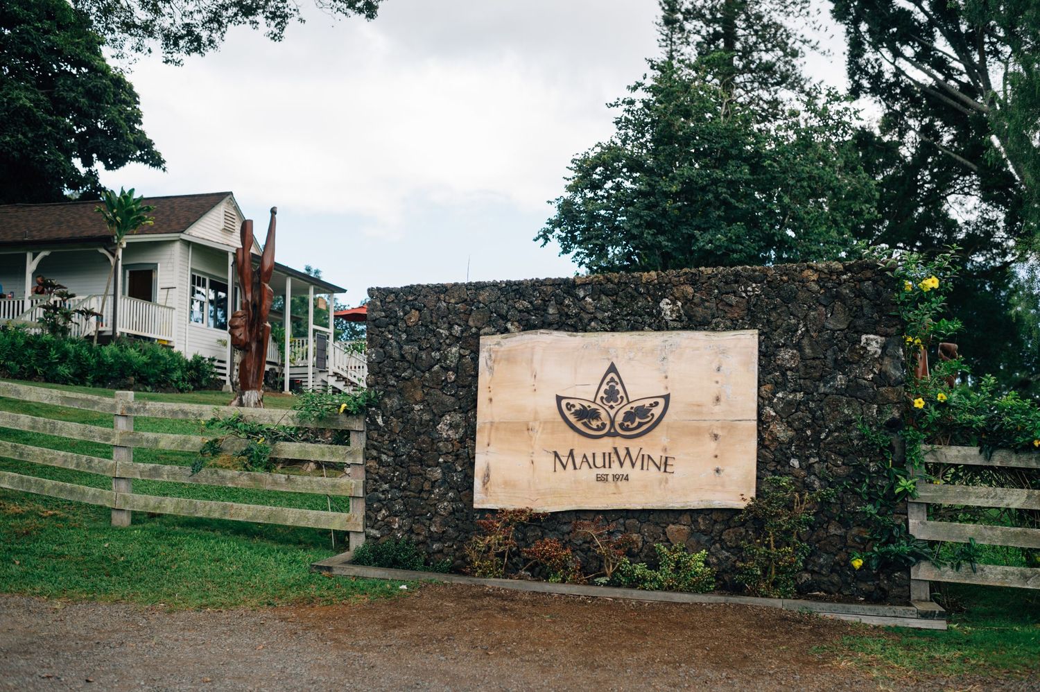 Stone entrance gate with wooden sign at a rustic winery or vineyard entrance.