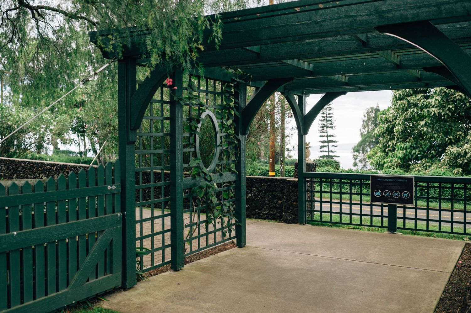 Green wooden pergola structure creating a shaded walkway in a garden.