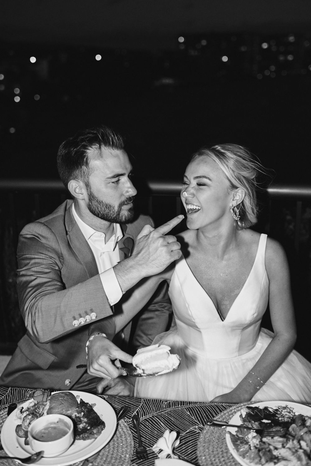 Newlyweds laughing together while enjoying their wedding dinner at night.