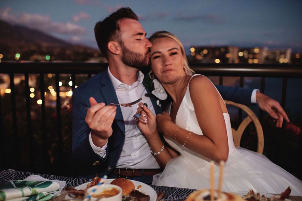 A couple shares a romantic moment during their wedding dinner at an outdoor reception.