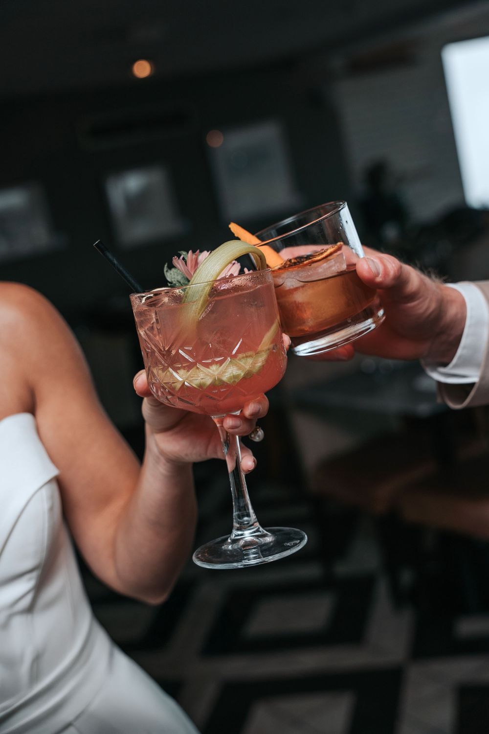Bride and groom clinking cocktails during their wedding celebration at Gara Rock, with pink and amber drinks garnished with citrus.