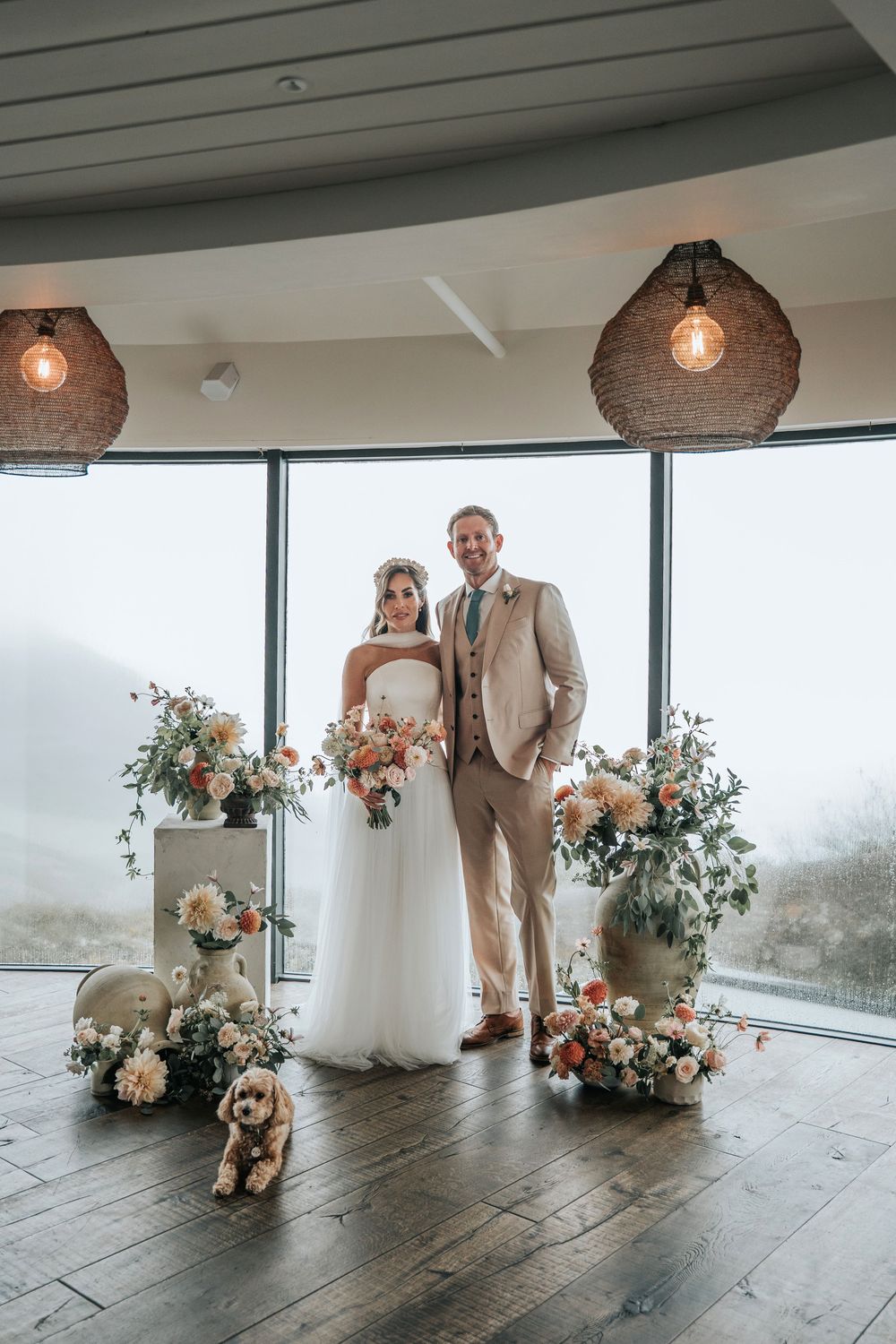 Bride and groom standing together during an intimate styled wedding ceremony at Gara Rock Hotel, framed by autumn florals with their dog sit