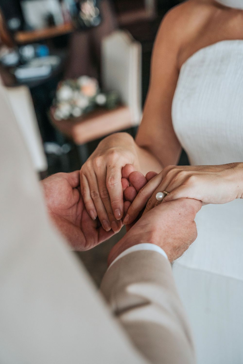 Close-up of hands during a styled wedding ring exchange at Gara Rock Hotel, capturing an intimate moment with soft natural light and neutral