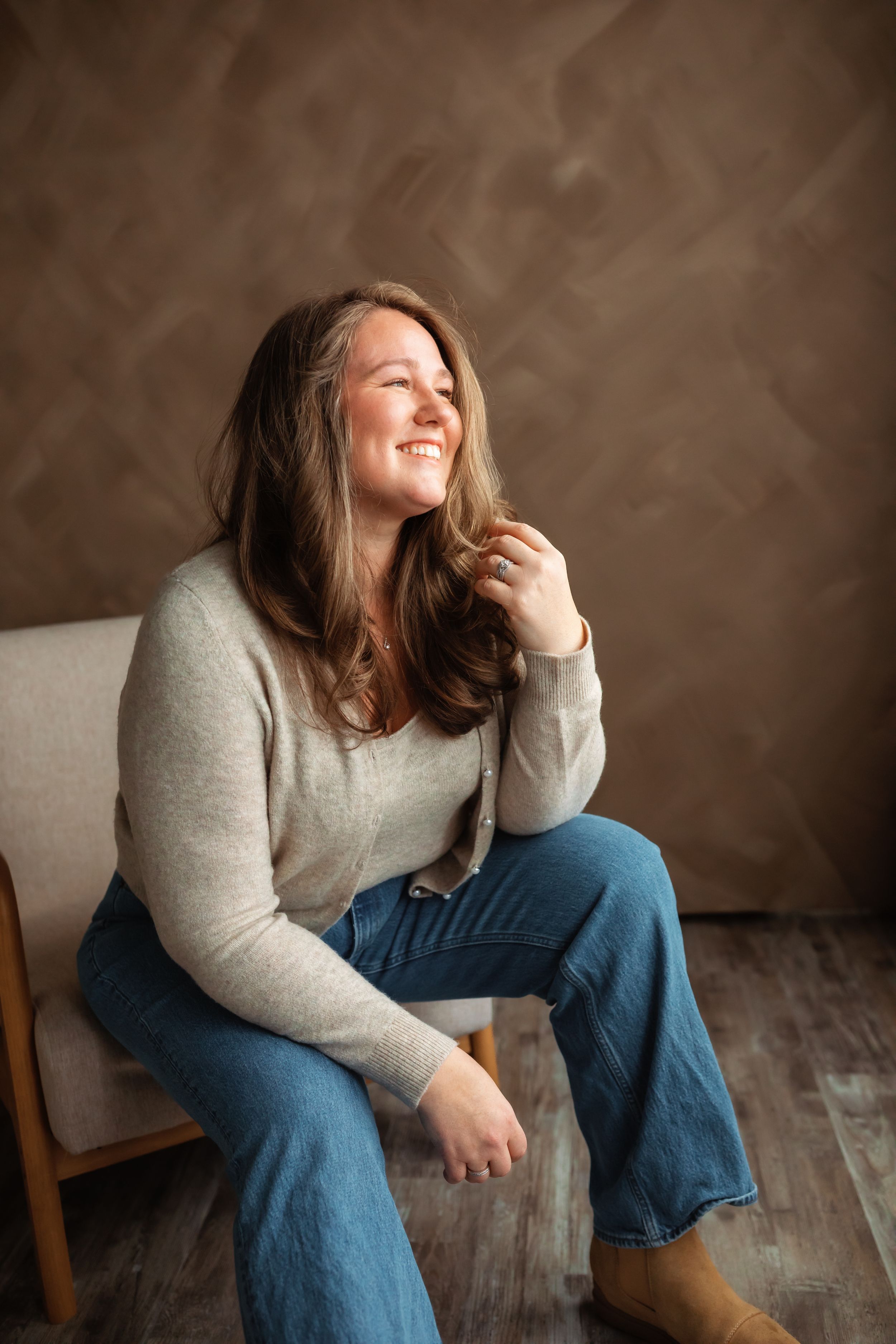 Woman in casual attire posing against white wall during indoor photoshoot.