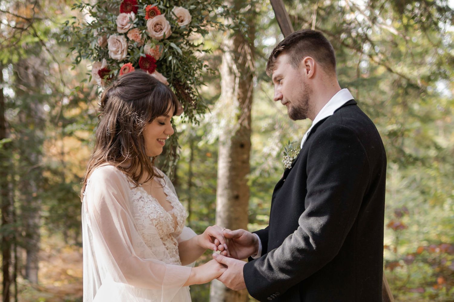 Eloping couple hold hands while exchanging vows in the woods in Mont Tremblant, Quebec, Canada.