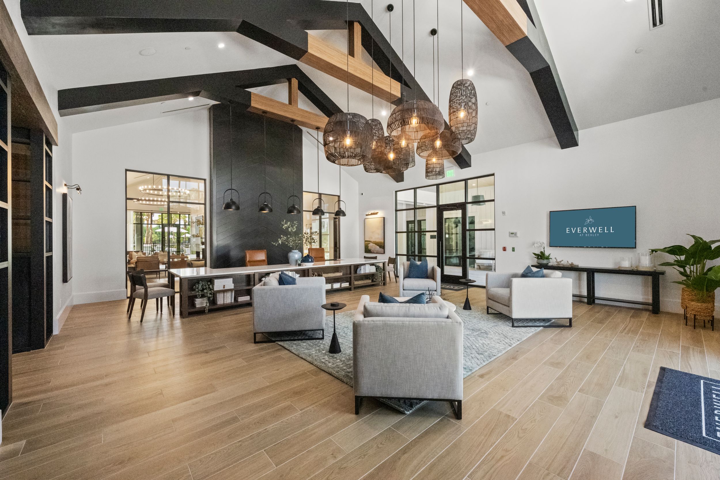 Modern apartment lounge with exposed wooden beams, grey sofas, hardwood flooring and contemporary pendant lighting.
