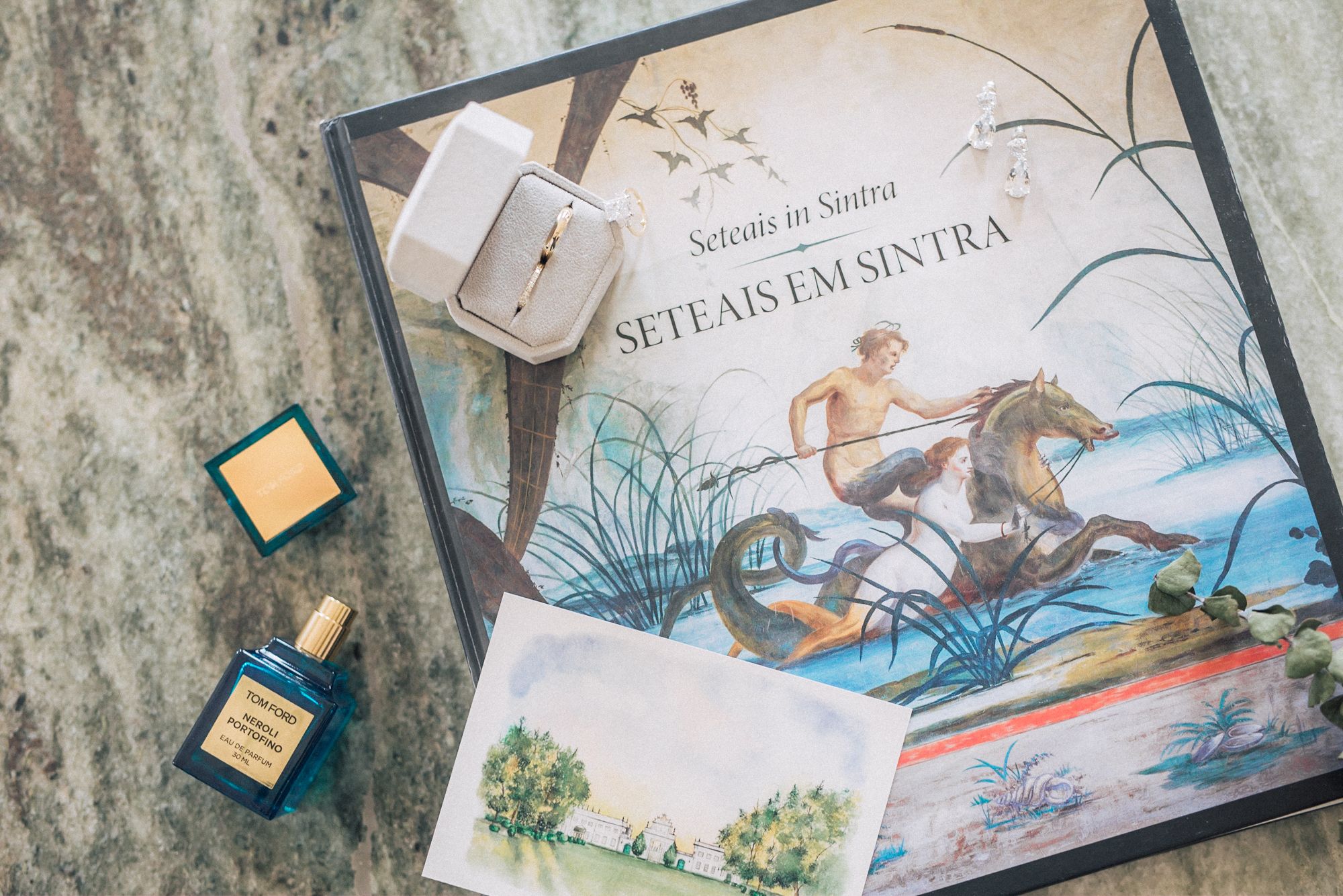 Wedding details flatlay with wedding rings, hand painted invitation, tom ford parfum on marble surface at Seteais palace. By lisbon wedding