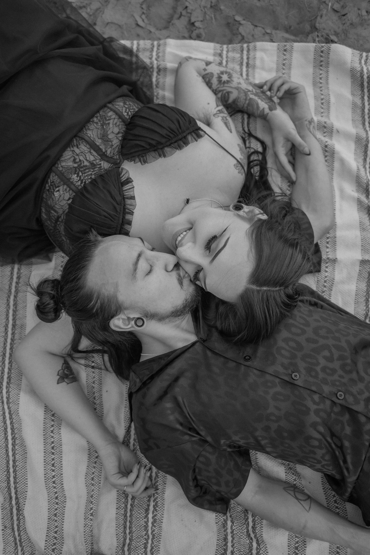 A black and white romantic photo of two people lying close together on a blanket. New Mexico engagement photographer. Queer photographer ABQ