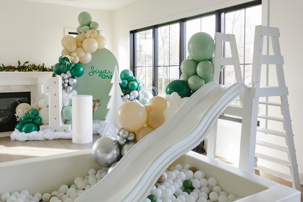 White slide, ball pit, and balloon decor at Siya's forest-themed first birthday. Captured by NYC family photographer Paula Brearley