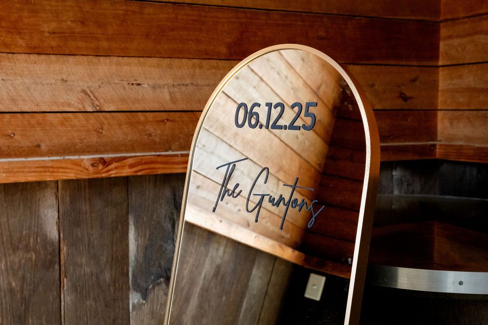 Custom engraved surfboard wedding sign displaying date 06.12.25 and The Gunlongs family name in rustic barn setting.