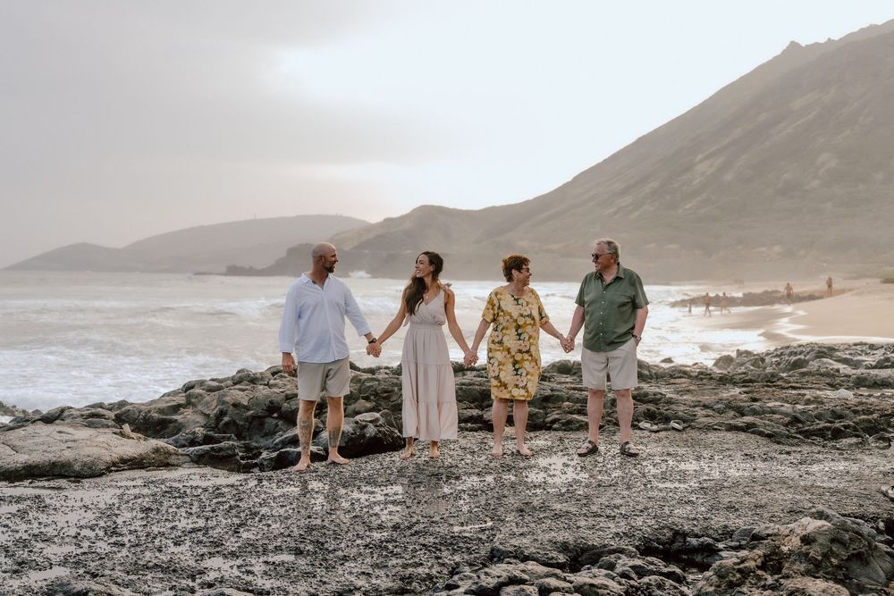 Family of four having a candid moment together during a beach photoshoot at golden hour.