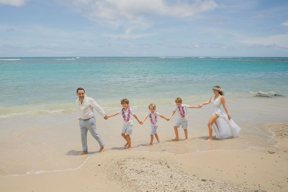 A group walking hand in hand along a pristine beach with turquoise water and blue sky in the background.