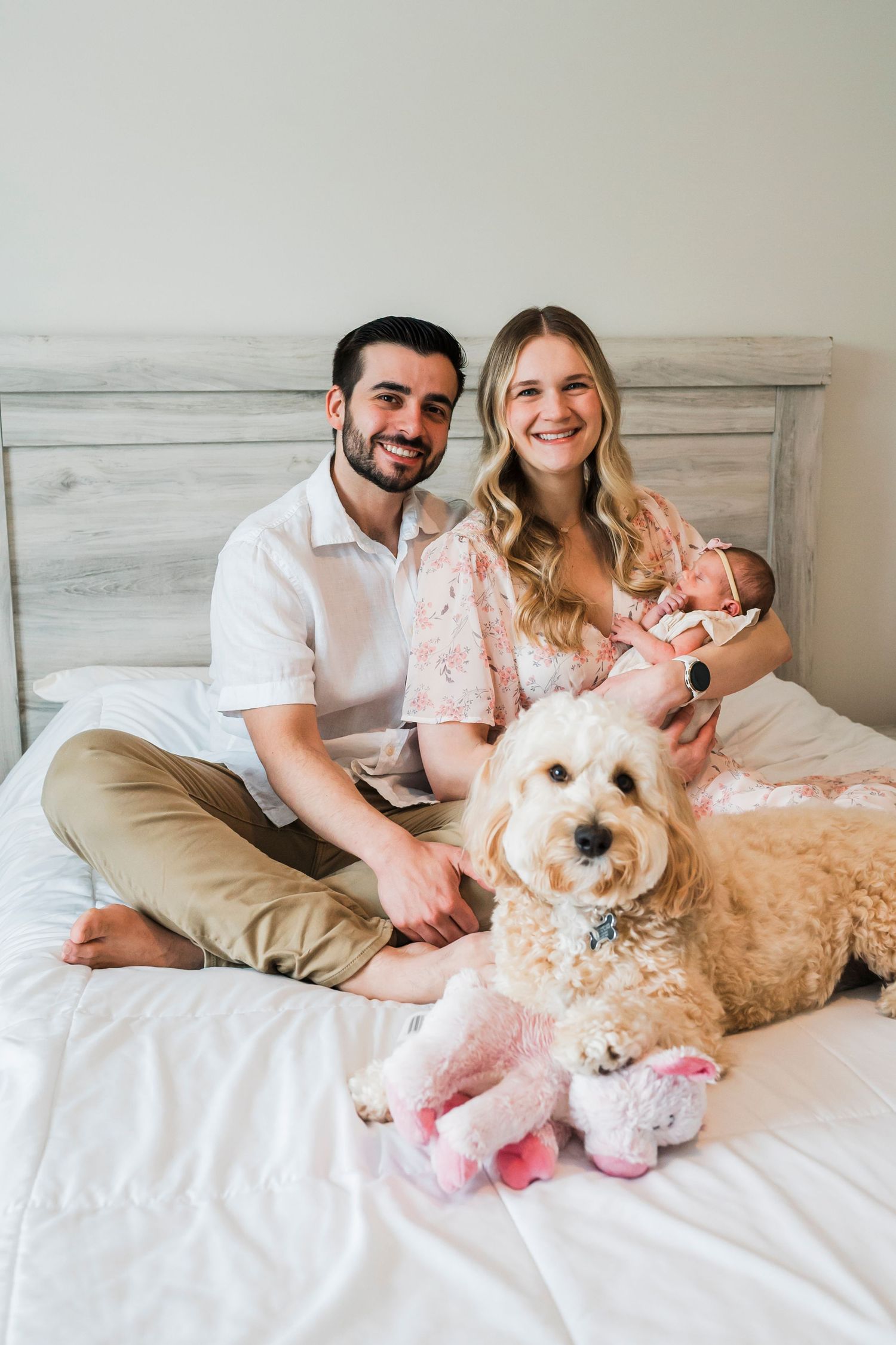 Family portrait under tree with floral decorations and golden retriever dog.