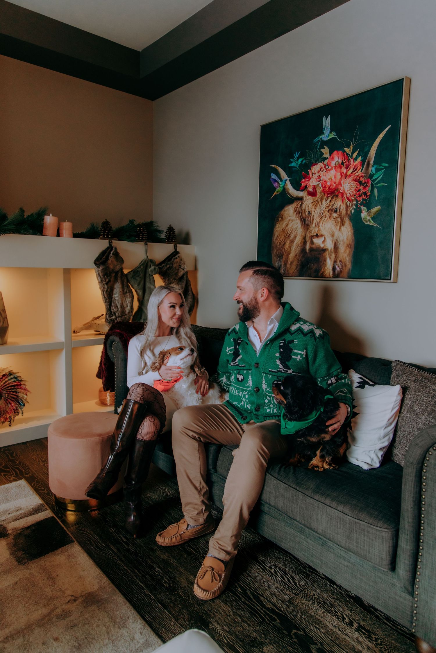 Couple sitting casually together on a dark gray couch in a living room with artwork on the walls.