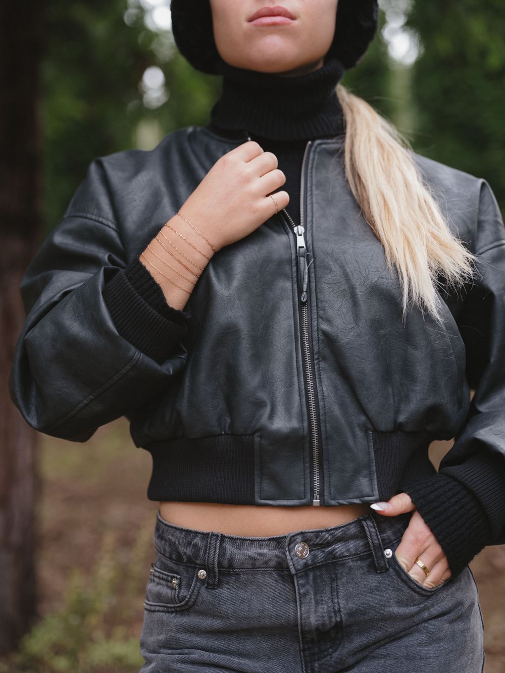 Black cropped bomber jacket with ribbed cuffs and hem shown against dark denim.