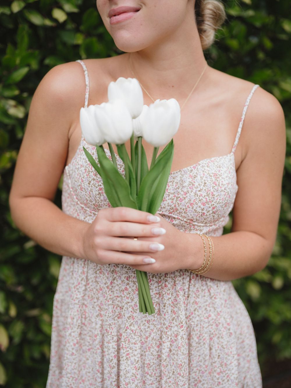 White tulip bouquet held against a floral printed dress with delicate straps.