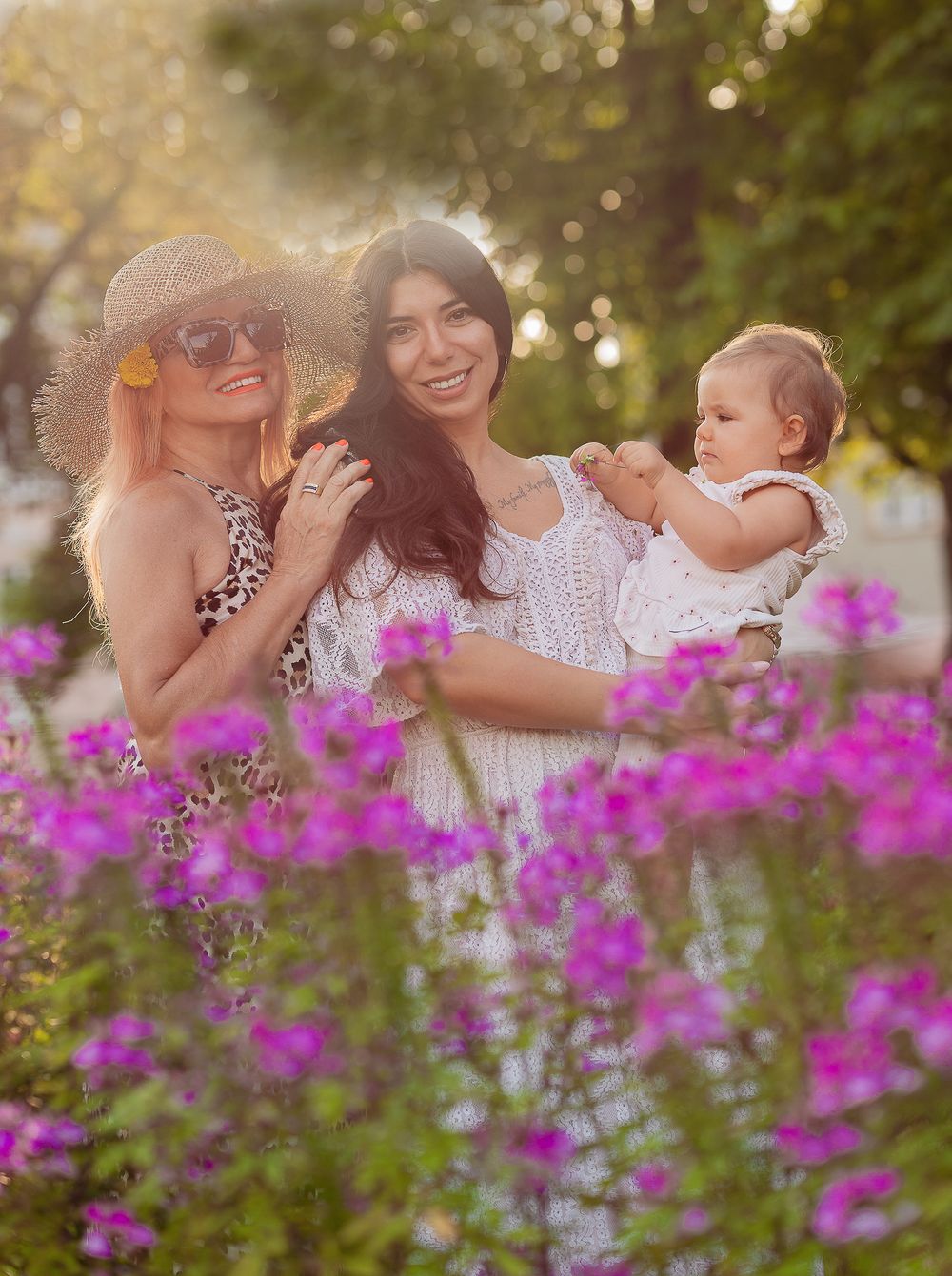 Familienfotografie - a candid summer moment of a kid, mother and grandmother among purple flowers.