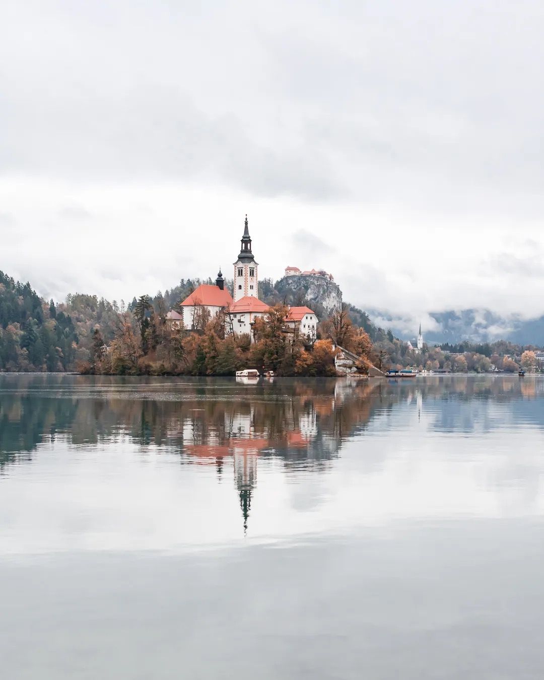 Lake Bled island with church at sunrise, reflected in the water.