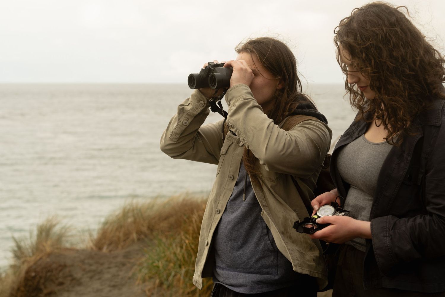Silhouetted figures hold hands on a wooden pier at sunset over a misty mountain lake.