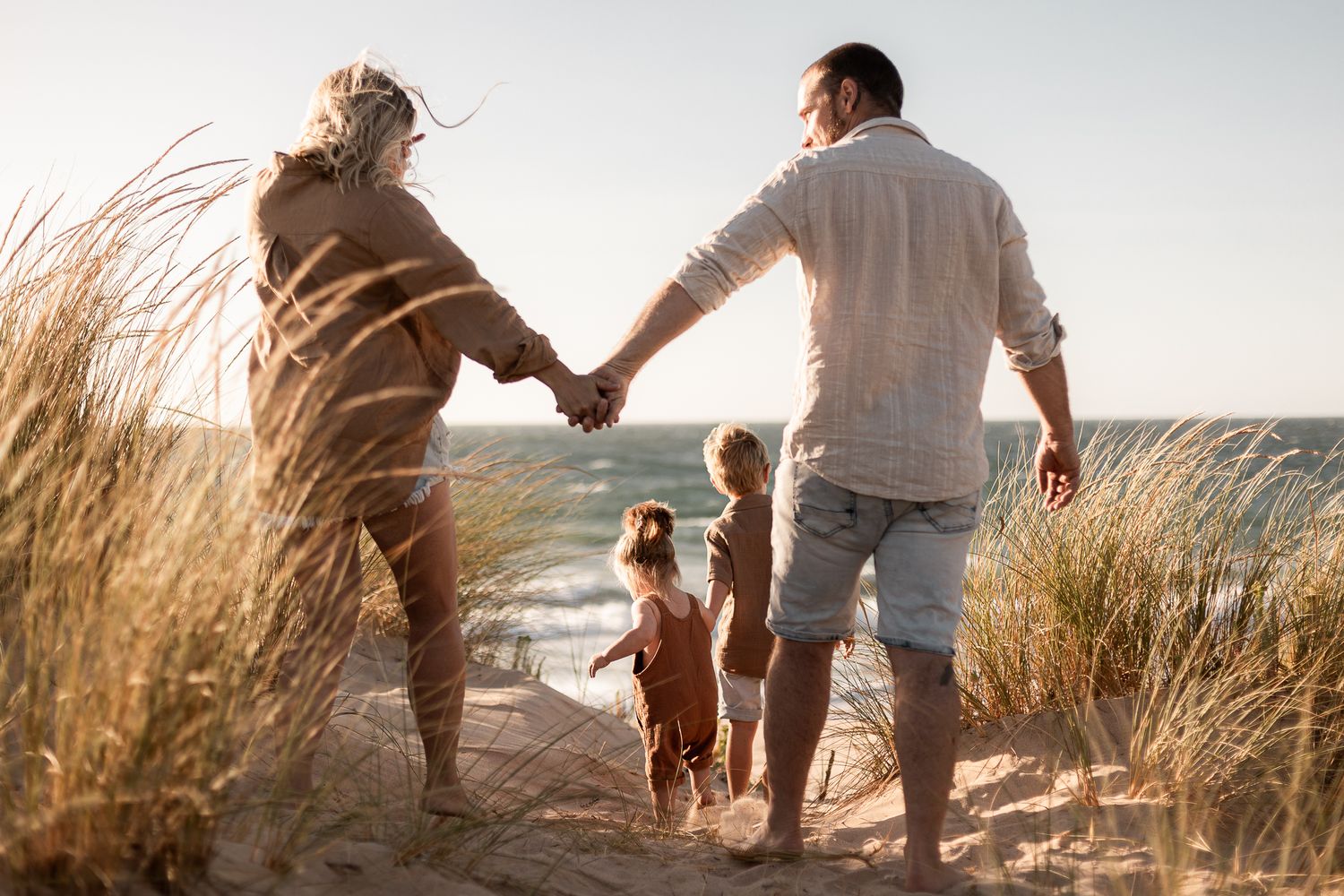 A beautiful young family enjoying a sunny day at the beach building sandcastles while the waves gently crash on the shore.