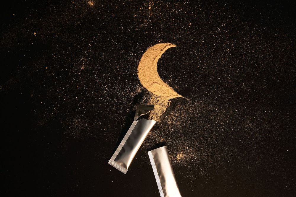 Two glass test tubes with golden glitter and a crescent moon shape against a dark starry background.