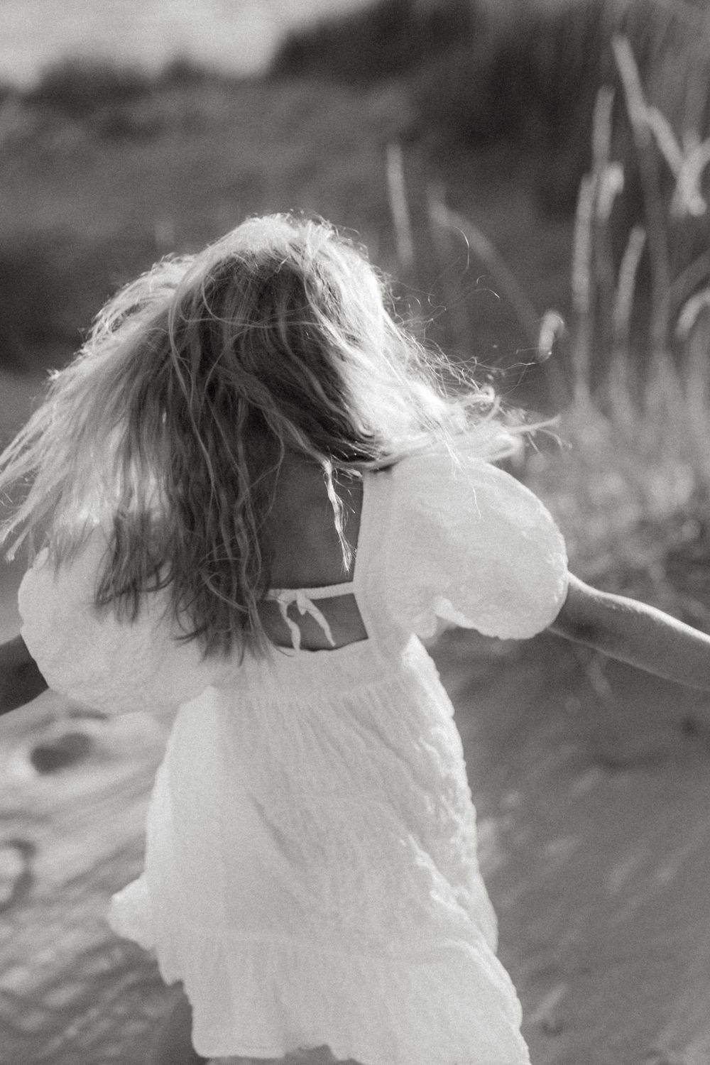 A black and white sequence of images shows hair blowing in the wind against a blurred background.