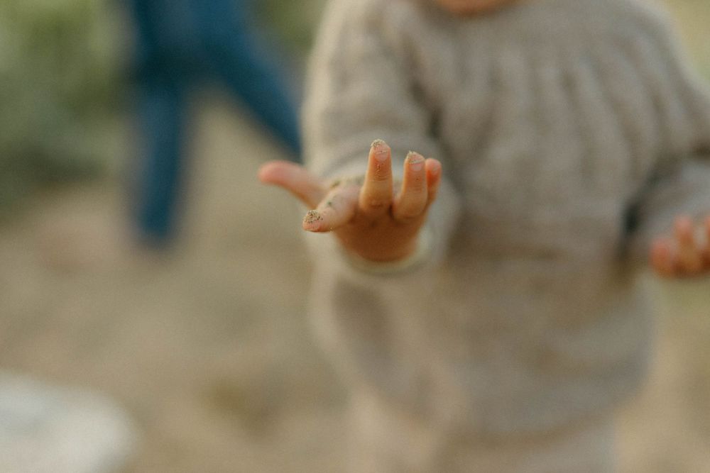 Hands in a circle performing a synchronized dance movement with fingers pointing upward against a blurred background.