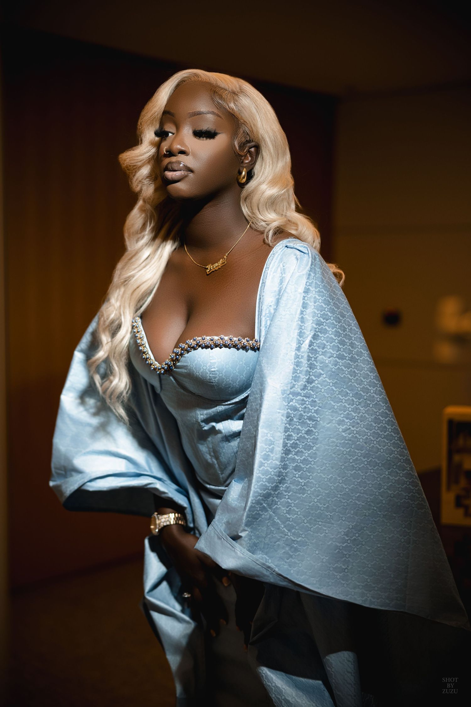 A person in a silver metallic outfit poses dramatically against a dark background in a series of artistic portraits.