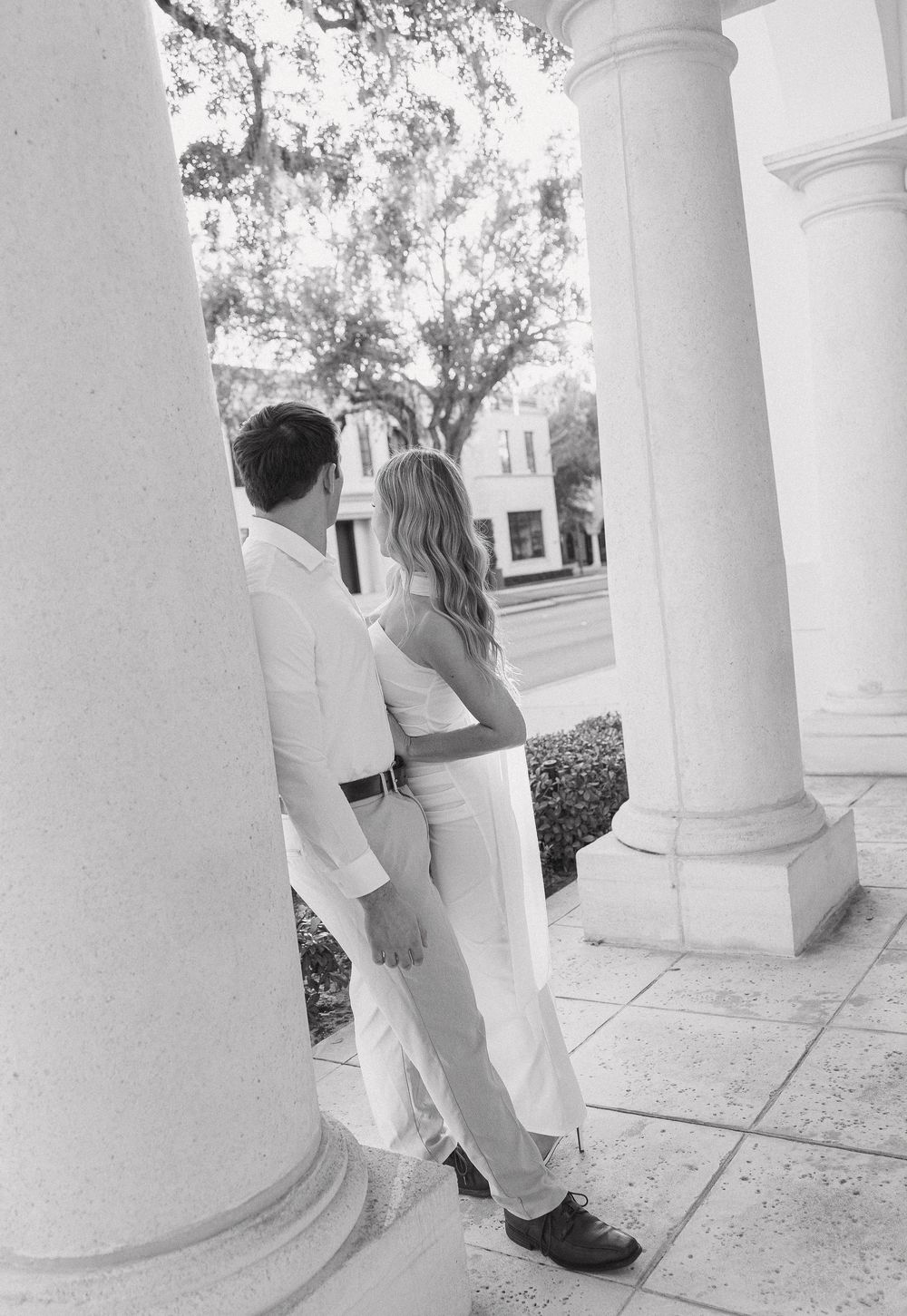 A series of black and white photos showing a person hiding behind white classical columns in a playful sequence.