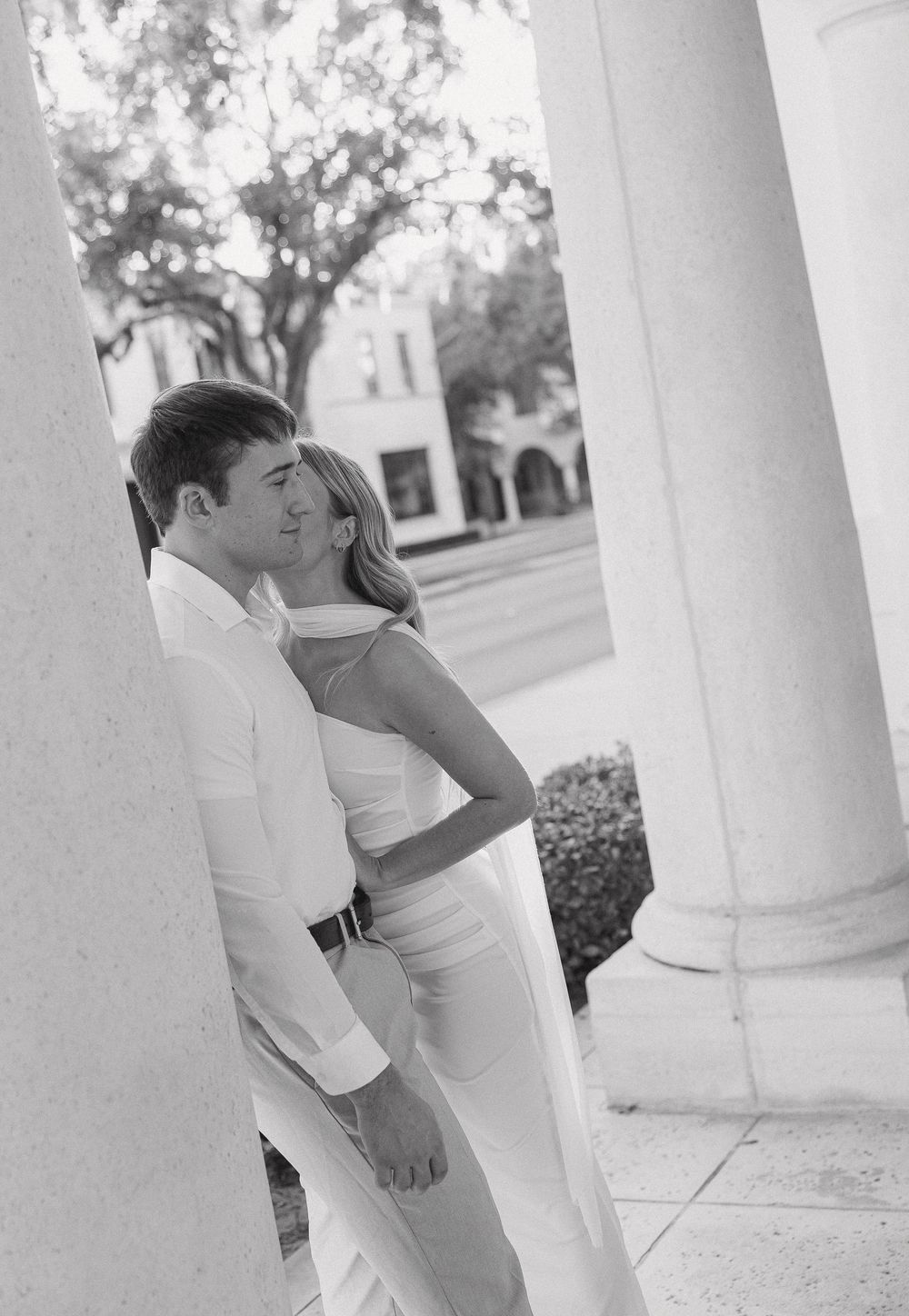 A black and white photo series showing someone playfully peeking around white columns in a sequence of four frames.