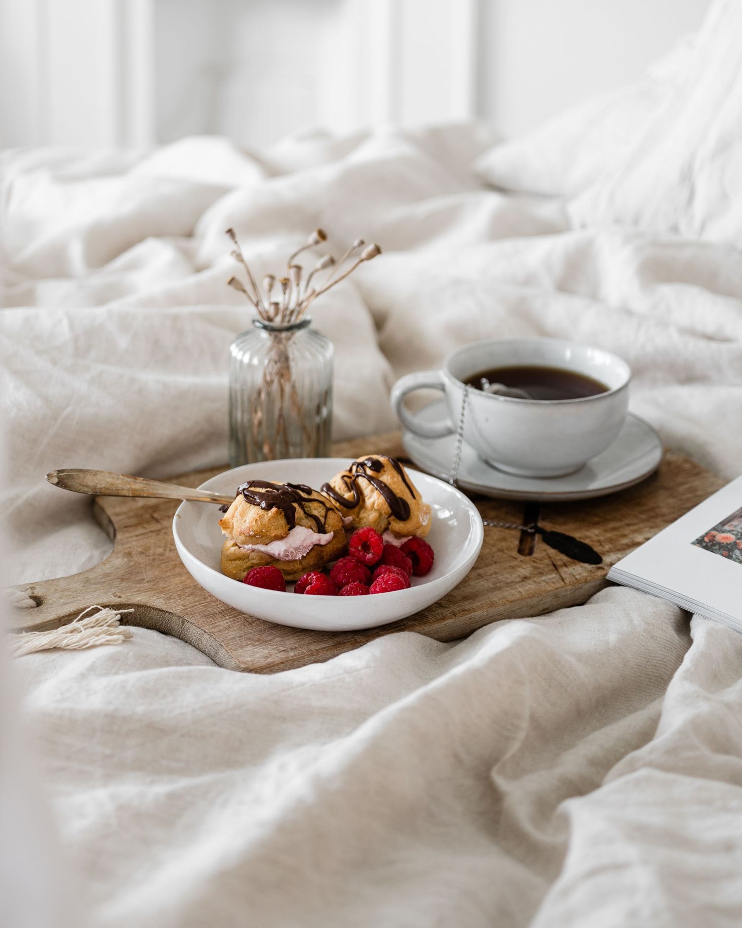 Rustic breakfast scene with coffee, pastries, and fresh strawberries on white linen and wooden serving boards.
